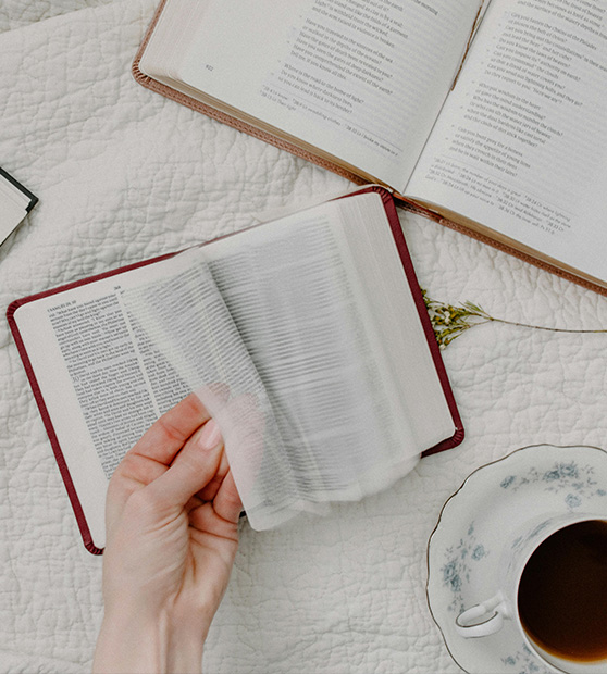 hand of person flipping pages with a coffee cup