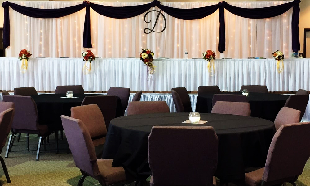 Head table area with lighted curtains, and tables decorated